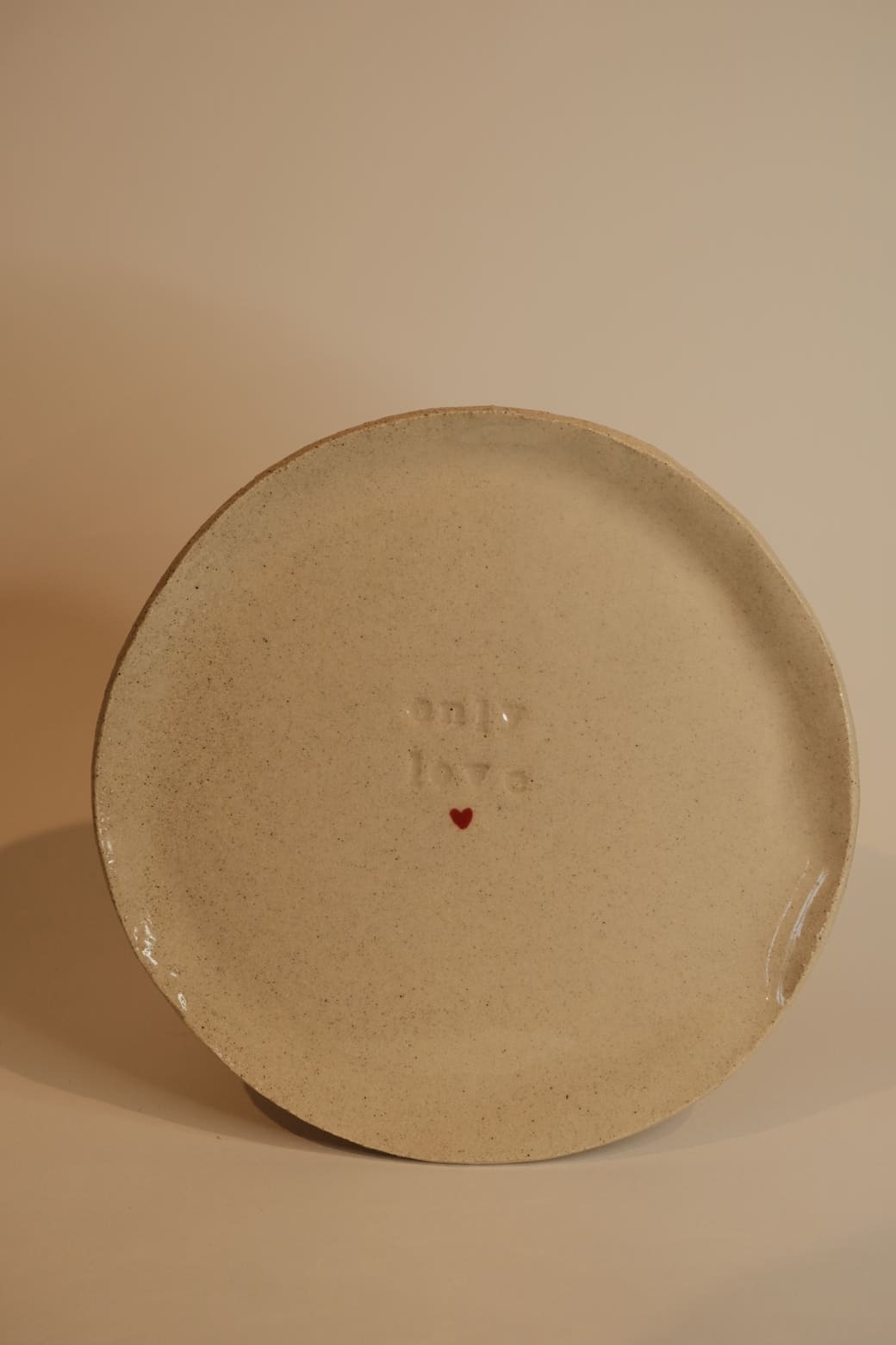 Petite assiette avec un cœur rouge au milieu et "Only Love" gravé.